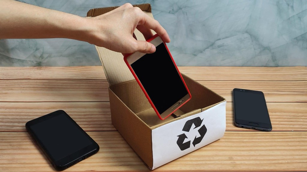 A hand placing a smartphone into a cardboard recycling box
