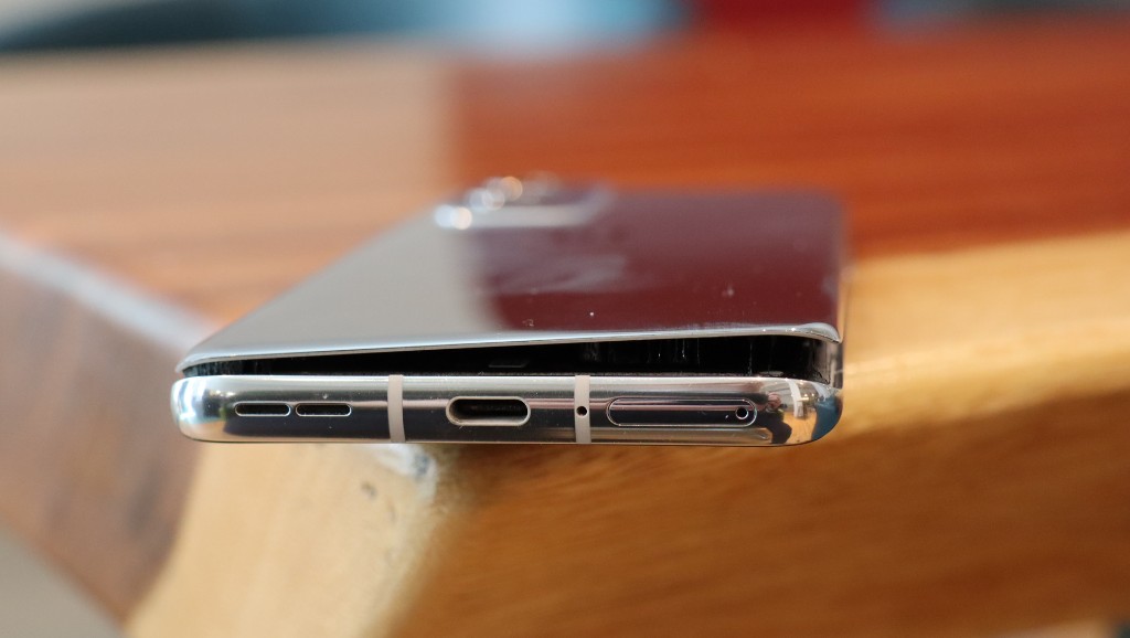 A silver phone with its screen visibly detached from the frame at the bottom edge from a swollen battery