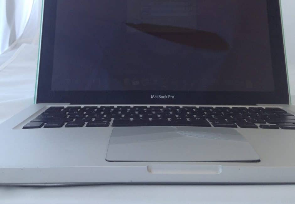 A MacBook Pro with a cracked trackpad pushed up by a swollen battery