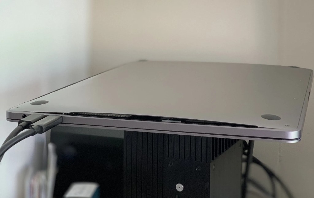 A MacBook Pro upside down with the bottom panel detached from the frame by a swollen battery